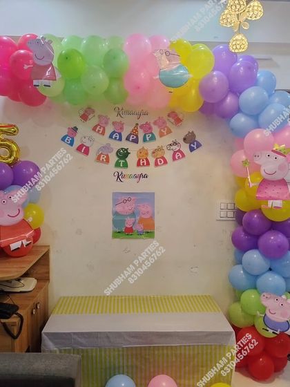 A fun Peppa Pig themed birthday decoration with a colorful balloon arch and character cutouts.