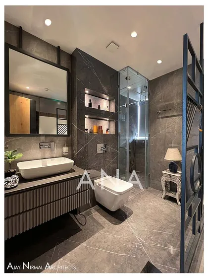 The master washroom in Apartment 704 uses a combination of light and dark grey tiles. Rose gold metal mosaic in the niches adds a touch of luxury and visual interest to the modern, functional space.
