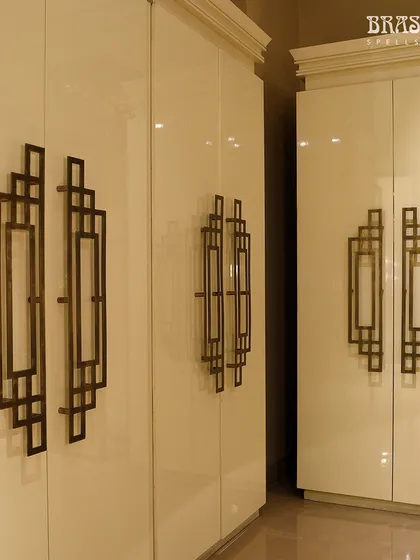 Here, the geometric handles are mounted on high-gloss white wardrobes. This pairing showcases the versatility of the design, proving it can complement both dark, moody interiors and bright, airy spaces with equal elegance.
