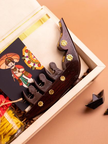 This image highlights the handcrafted wooden snake boat (Chundan Vallam) replica, a standout piece in my 'Onasanchari' hamper that celebrates the famous boat races of Kerala.
