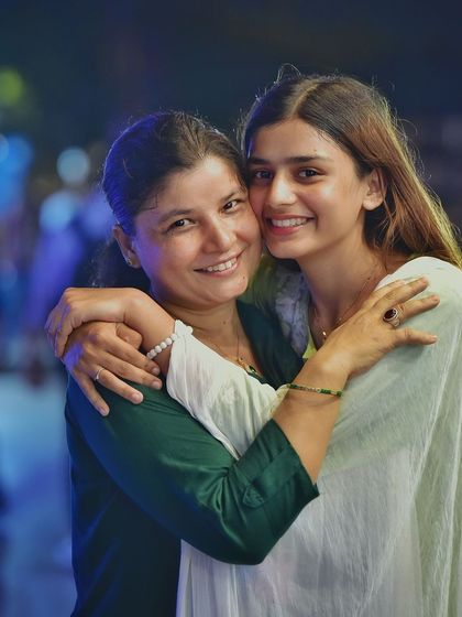 A beautiful, heartwarming portrait of a mother and daughter. Their embrace and the soft, colorful lights of the night market create a truly special and emotional moment.