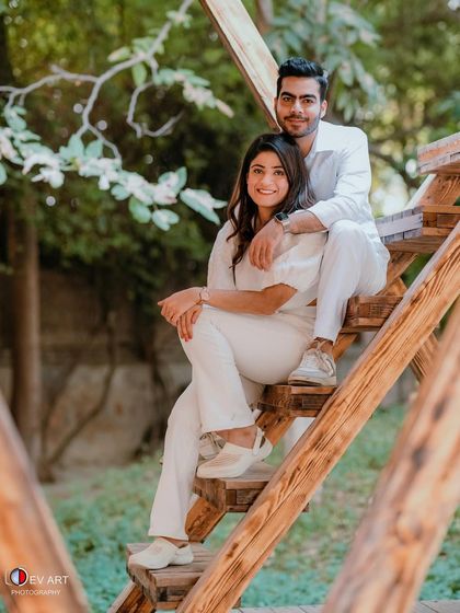 A full shot of the couple in a relaxed, outdoor setting. The makeup is natural and photogenic, perfect for capturing these casual moments.