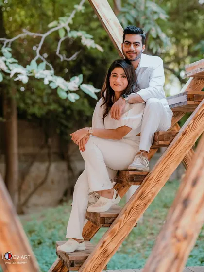 A full shot of the couple in a relaxed, outdoor setting. The makeup is natural and photogenic, perfect for capturing these casual moments.