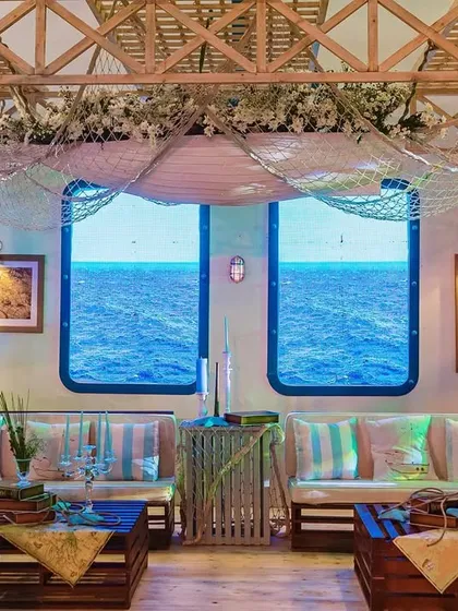 A comfortable lounge area designed to look like the inside of a ship's cabin. The windows are actually screens displaying a view of the open ocean, enhancing the immersive experience.