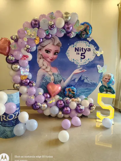 Full setup for a Frozen party, showing the circular backdrop, balloon garland, and themed pedestal.