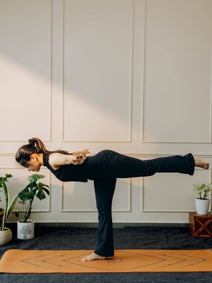 A powerful Virabhadrasana III (Warrior III) with arms bound back, emphasizing core strength and stability.