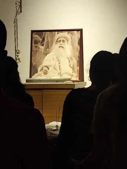 Silhouetted against the light of the Guru's presence, seekers stand in quiet reverence. The Sadhguru Sanidhi Pooja is a time for inner communion and stillness.