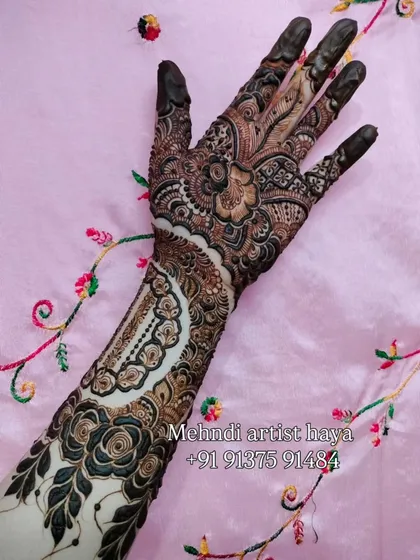 A unique bridal design featuring a large, intricate cuff on the forearm with negative space, paired with bold floral work on the hand.