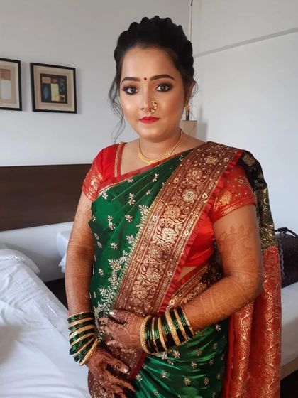 The 'after' reveal. A complete traditional Marathi bridal look, featuring a beautiful green and red saree, classic jewelry, and makeup that highlights her natural elegance.