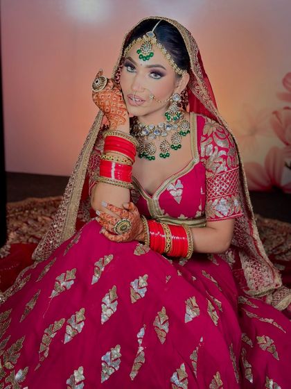 A beautiful bride in a magenta lehenga. The makeup features a soft pink and purple eye look to match her outfit, along with flawless, glowing skin.