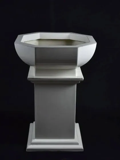 A classic pedestal planter made of fiber. This elegant design is perfect for entranceways or as a standalone feature in a garden.