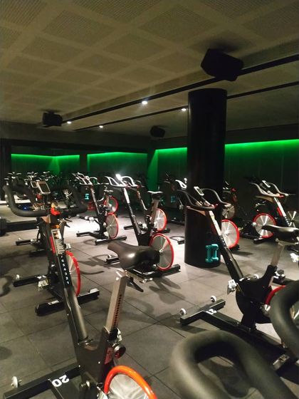 A full view of the spinning studio setup, showing the arrangement of bikes for optimal instructor visibility and class flow. The acoustic ceiling panels were installed to manage sound in the high-energy environment.