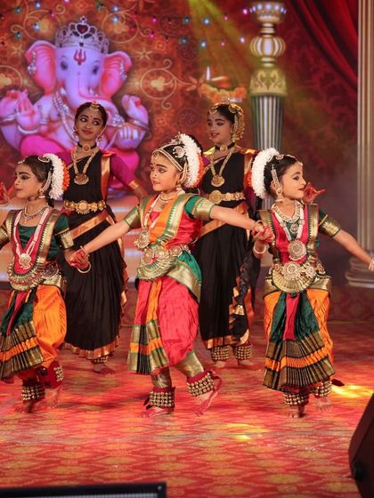 Our young dancers performing in front of a Ganesha backdrop, invoking blessings at the start of a performance. The vibrant costumes and stage setup add to the festive atmosphere.