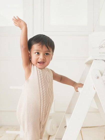 Waving to all his fans. This little one is celebrating his first birthday in style, standing tall and happy.