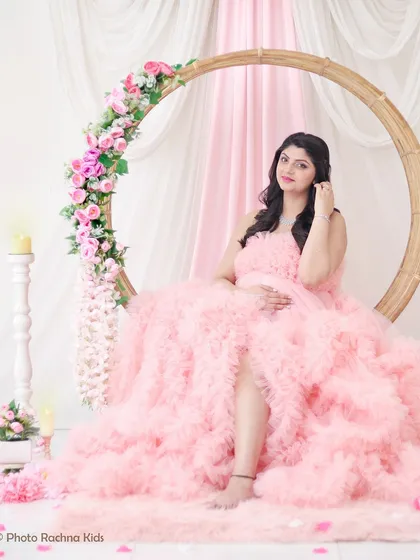 A dreamy solo portrait in a cloud of soft pink ruffles. This setup, with a circular floral arch, creates a whimsical and romantic setting.
