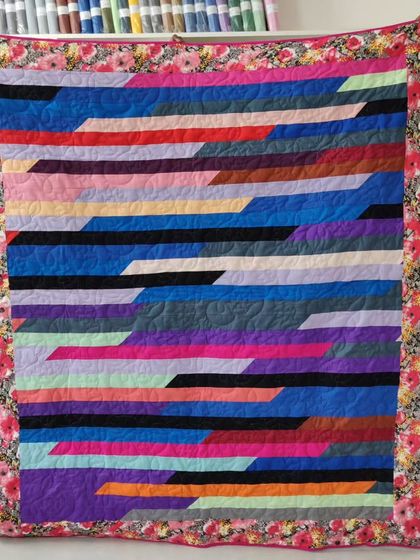 A modern jelly roll quilt with diagonal stripes of various colors.