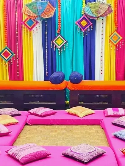 We arrange comfortable and colorful floor seating for guests to match the Mehendi or Sangeet theme. This setup includes low benches, mattresses, and a variety of printed and solid cushions for a relaxed atmosphere.