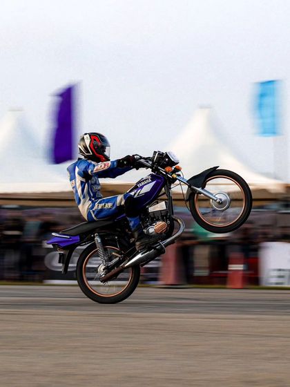 A rider performs a wheelie on a classic Yamaha RX-series bike. The skill to control these lightweight, powerful two-strokes is incredible to watch.