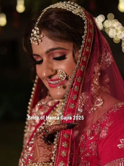 A stunning bridal portrait with beautiful bokeh lighting. The bride's downward glance is serene and elegant, highlighting her makeup and the mehendi on her hands.