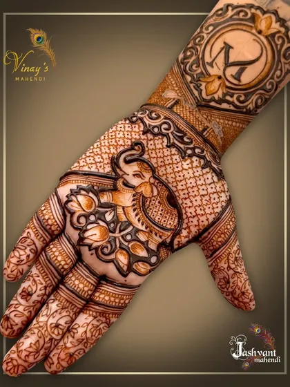 A beautiful design featuring a lotus-loving elephant on the palm and a personalized initial 'K' in a decorative circle on the wrist.