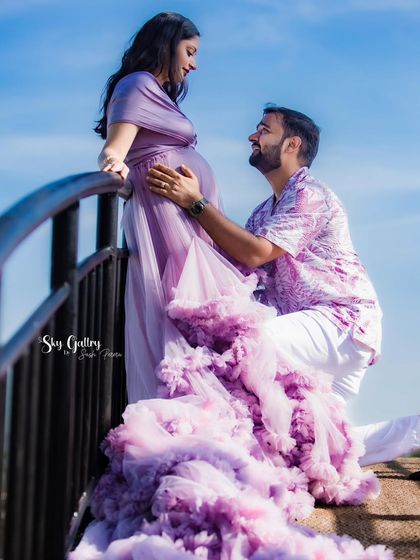 A loving moment between the parents-to-be during their destination shoot. The partner kneels to connect with the baby, a beautiful pose that highlights the flowing lavender gown.