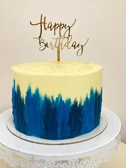 This red velvet cake with cream cheese frosting gets an artistic touch. The bottom half is decorated with a hand-painted, abstract brushstroke effect in shades of blue, creating a modern and eye-catching design.