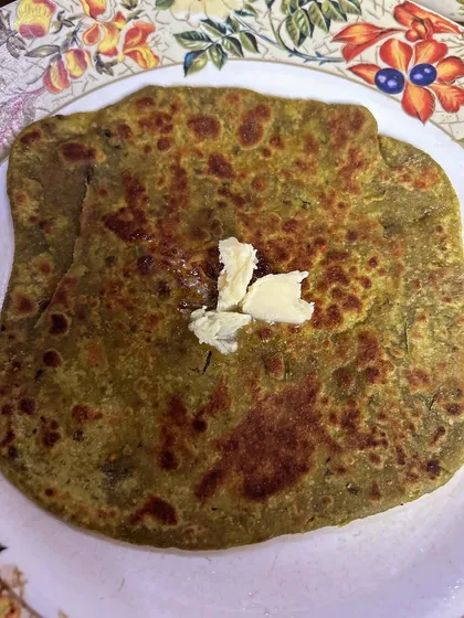 A healthy and tasty Palak Paratha (spinach flatbread) with a dollop of white butter on top.
