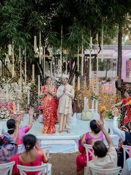 A moment of blessing and celebration as guests shower the couple with flowers and rice during their outdoor Maharashtrian wedding ceremony.
