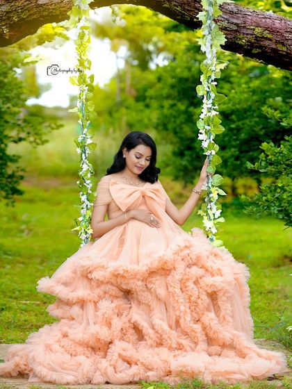A dreamy portrait on our floral swing. The mother-to-be looks like a princess in a voluminous peach-colored ruffled gown.
