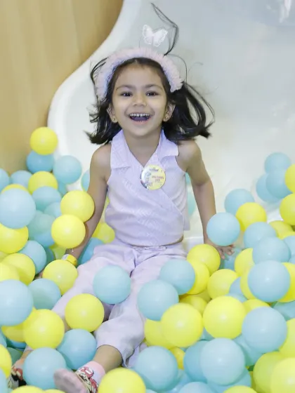 A joyful birthday girl having a blast as she slides into one of our colorful ball pits.