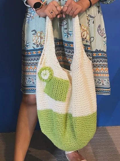 A customer happily holding her custom tote bag. This one is in green and white and features a small outer pocket with a flower detail.