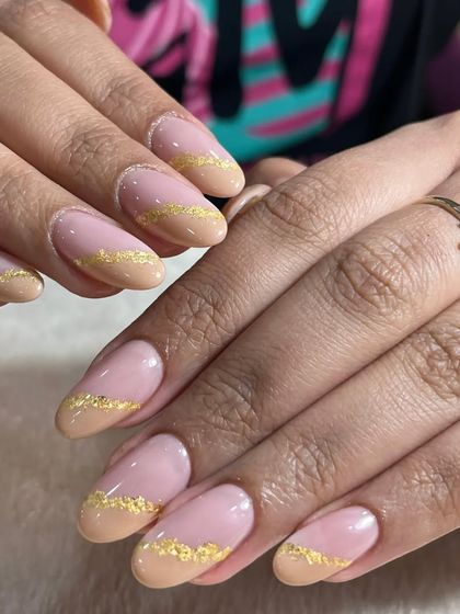 A beautiful and elegant design featuring a nude base with gold foil glitter at the tips, creating a modern and sophisticated take on a French manicure.