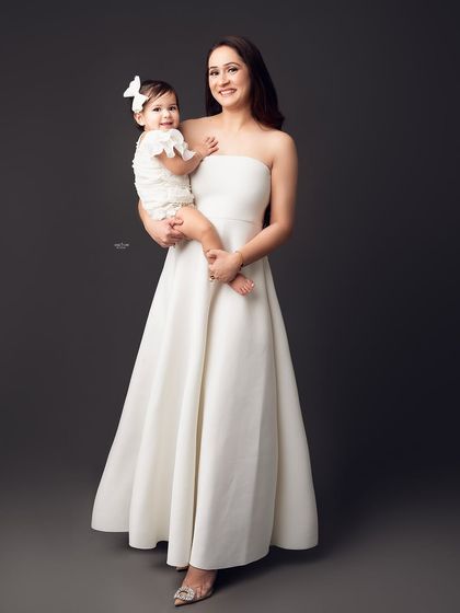 A stunning portrait of a mother in a beautiful white gown holding her sweet baby girl.