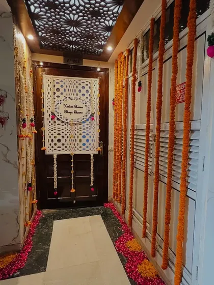 An elegant entrance decoration for a home. The door is decorated with marigold garlands and a custom nameplate for the couple, creating a personalized welcome.