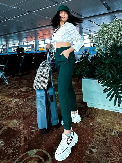 A hair-flip moment at the airport. The cropped shirt and joggers are a comfortable yet stylish combination for travel.