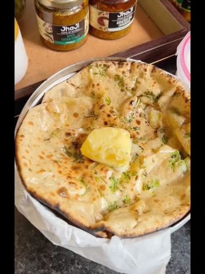 A close-up shot of a fluffy aloo paratha with a dollop of butter, ready to be enjoyed with our pickles.