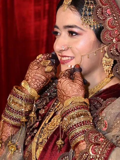 A happy, candid moment showing the bride adjusting her nath. Her joy and the beautiful makeup details are on full display.