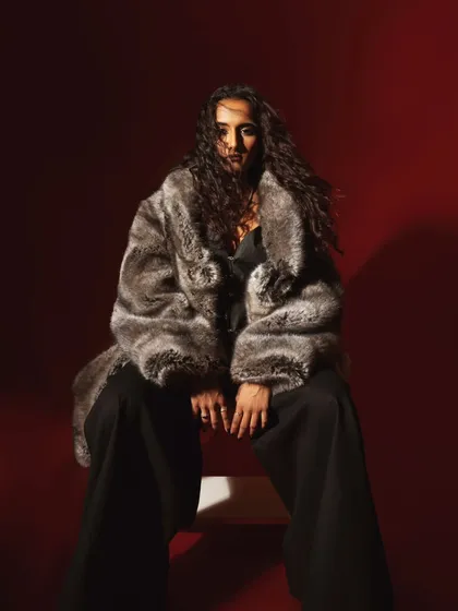 A more mysterious shot from the same series, where the model's face is partially obscured by her hair. The focus is on the texture of the fur and the overall mood.