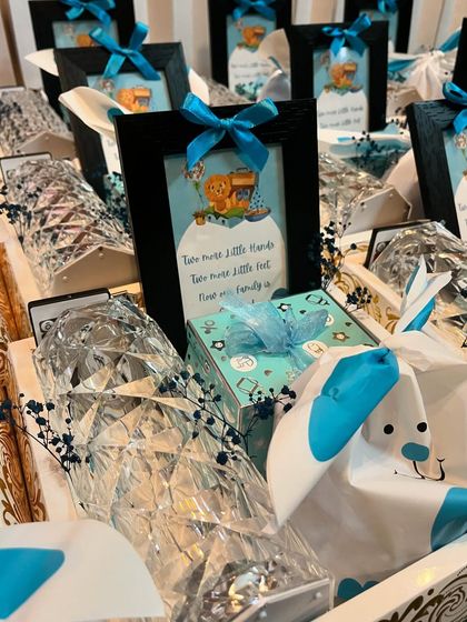 A closer look at the baby announcement hamper, featuring a small framed picture with a sweet poem, surrounded by beautifully wrapped gifts in a blue and white theme.