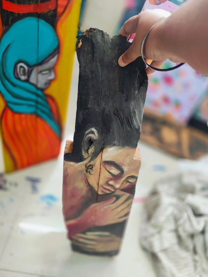 A powerful sculpture-like painting on a piece of reclaimed wood, showing an intimate embrace. This is available for purchase.