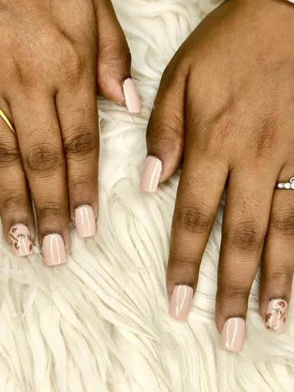 An elegant nude polish on short square nails, featuring a subtle leopard print accent nail with gold foil details.