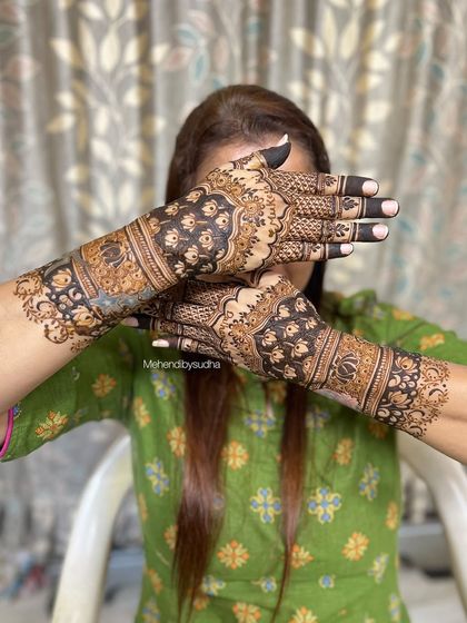 The back of the hands for a semi-bridal design, featuring bold floral work with dark-filled areas for a striking look.