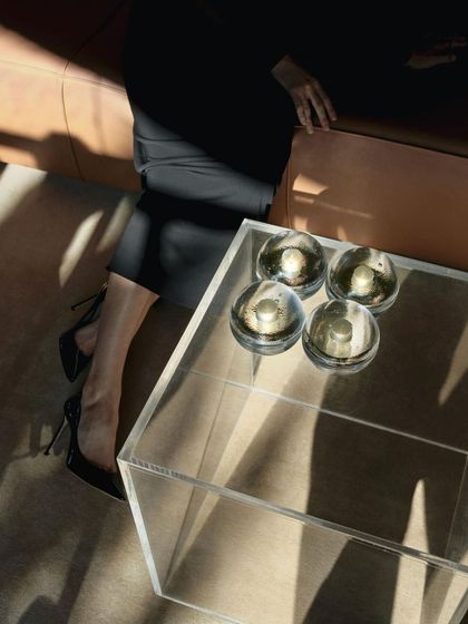 Four Bocci 14p lamps sit on a clear acrylic table, their light casting beautiful shadows and reflections.