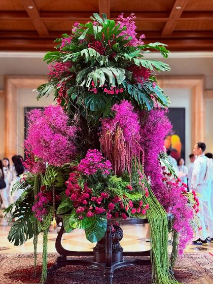 A full view of the pink and green tropical installation, showcasing its dramatic height and lush, cascading form. This is what I mean by living art, a piece that has presence and movement.