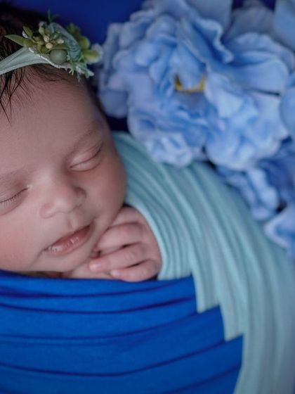 Dreaming in blue. I use color-coordinated wraps and props, like these blue flowers, to create a cohesive and artistic portrait of your swaddled baby.