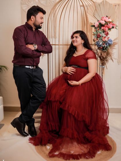 A sweet couple's shot during an indoor maternity session. The rich maroon of the gown complements the partner's shirt, creating a coordinated look.