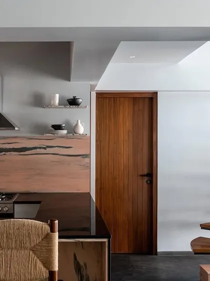 A view of the kitchen, featuring a dramatic pink marble backsplash and a dark countertop. I designed this space for a restaurateur, focusing on durable surfaces and a professional-grade layout.