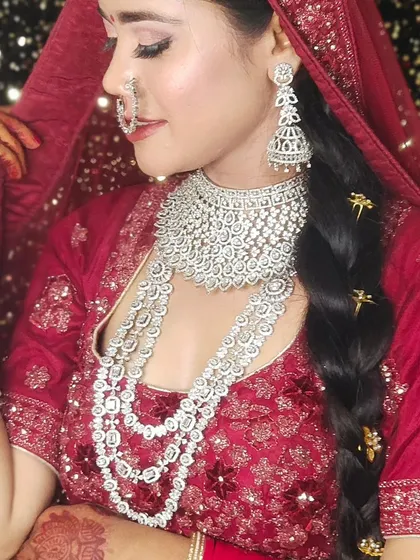 A bride wearing a heavy, layered American Diamond set with her red lehenga. The braided hairstyle with accessories completes this glamorous look.