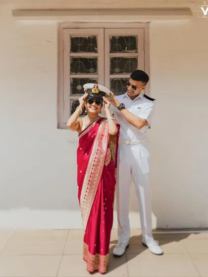 A playful and sweet moment between the bride and groom. He places his Navy cap on her head, and her joyful smile says it all.