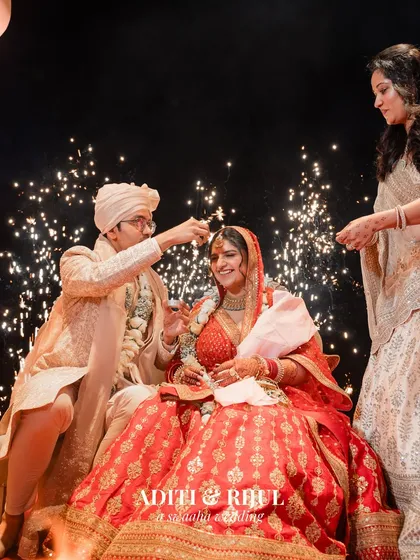 The groom applying sindoor, a significant and emotional ritual, beautifully lit by the glow of the sacred fire and sparklers.